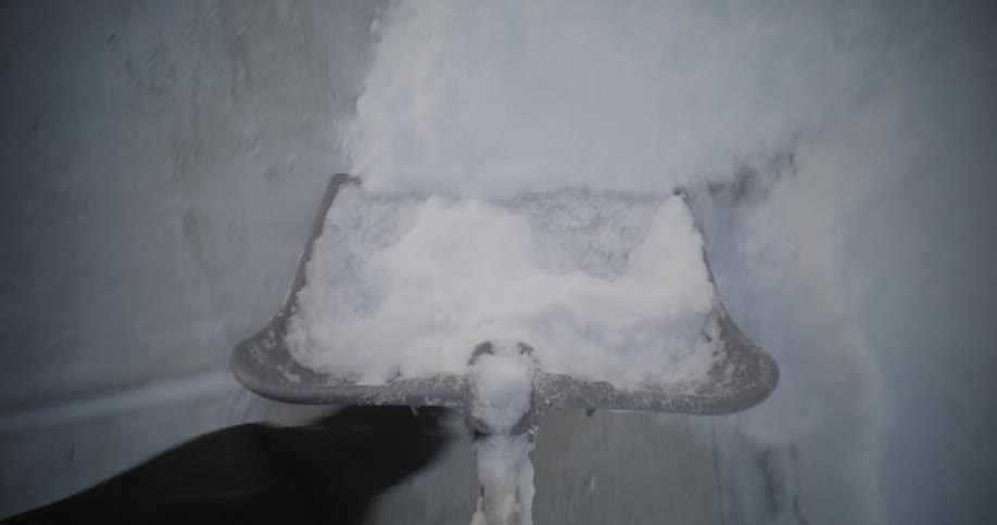 A person is using a metal shovel to remove snow