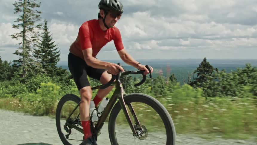 A man riding a gravel bicycle on forest road up a mountain