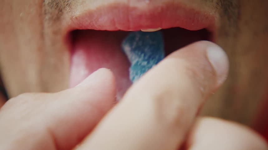Close up of mouth watinbg a blue sourpatch candy