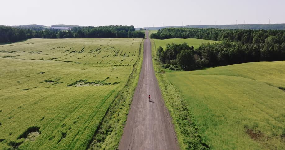 Aerial of a gravel cyclist riding a bicycle downhill on a dirt road