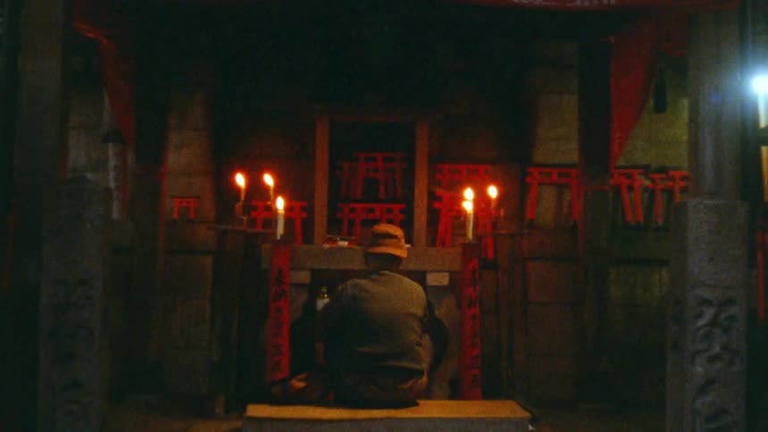 A man is in front of a shrine with lit candles