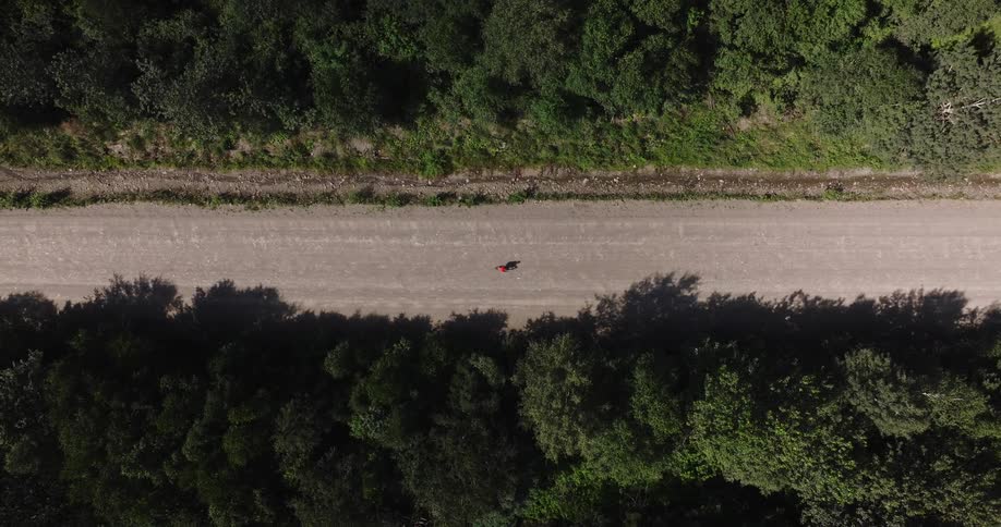 Bird eye's view of a gravel cyclist riding his bike on a straight dirt road