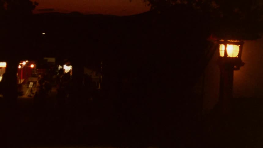 Crowd walks through the inside of a building at night while red tints the horizon