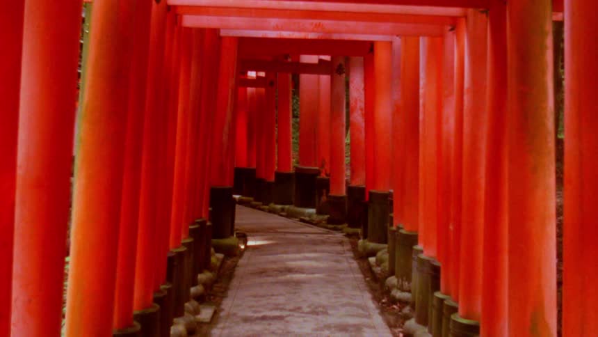 Red columns with cross beams form a covered walkway during the daytime