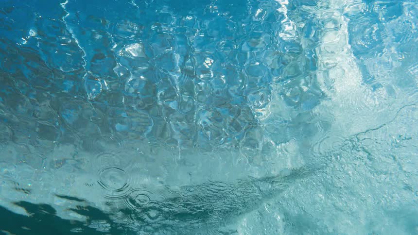 An underwater view with light filtering through the surface as a wave rolls overhead
