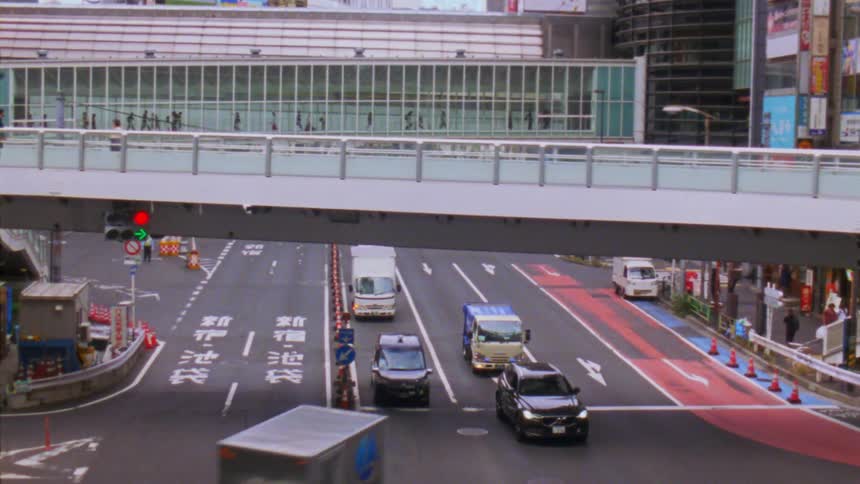 Traffic flows smoothly beneath a pedestrian overpass in a japanese city