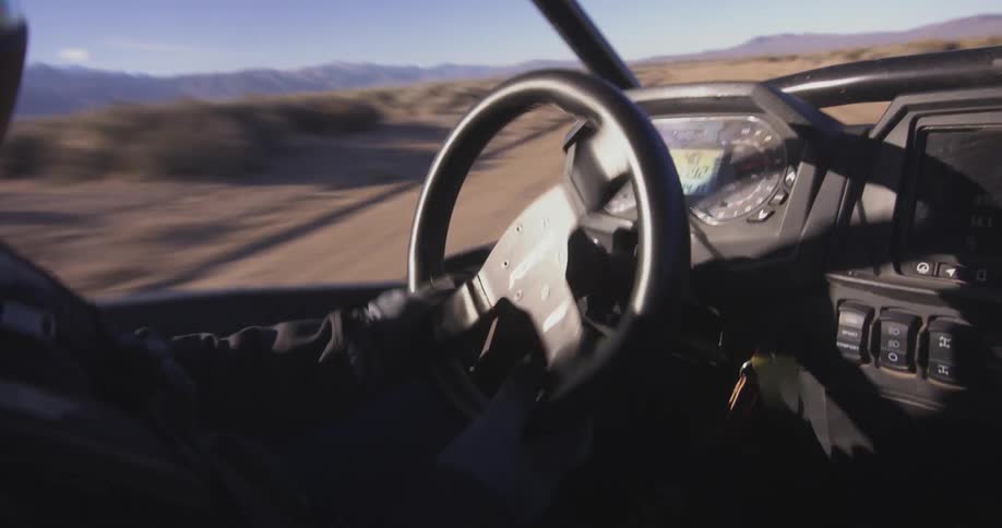 A person is yanking the steering wheel back and forth in the desert