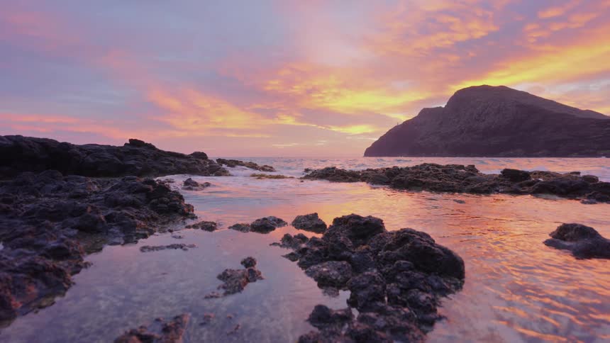 Small waves break onshore as they hit the rocks