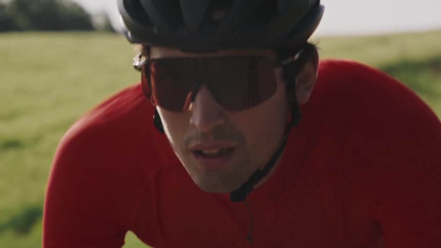 Close-up of a gravel bike cyclist riding down a hill in a grassy field