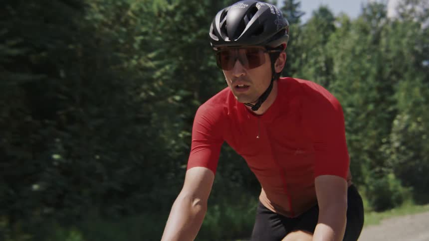 Follow and zoom-in on a male gravel cyclist riding a forest road deep in the woods