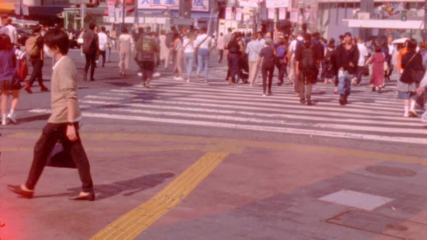 A busy urban crosswalk with numerous pedestrians walking in various directions