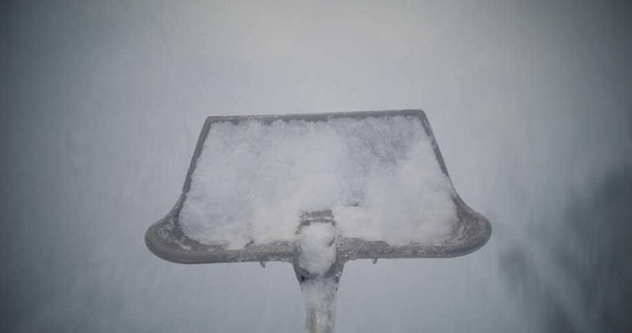 A person throws snow after scraping it from the sidewalk
