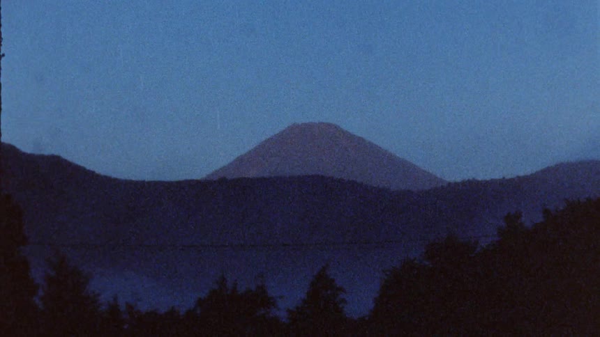 A lone mountain peak is seen past other mountains
