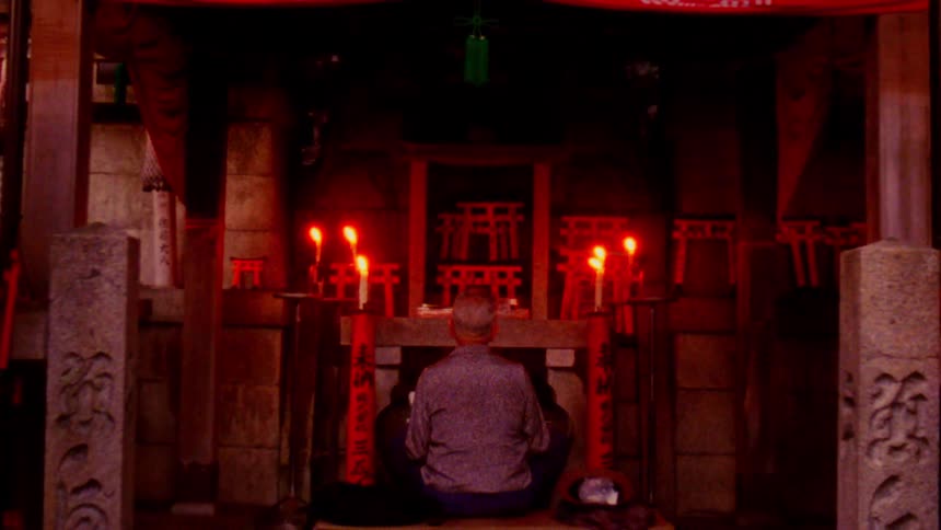 Man prays at a shrine near a forest