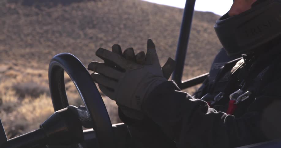 A man in a dune buggy puts on his gloves as he gets ready to drive