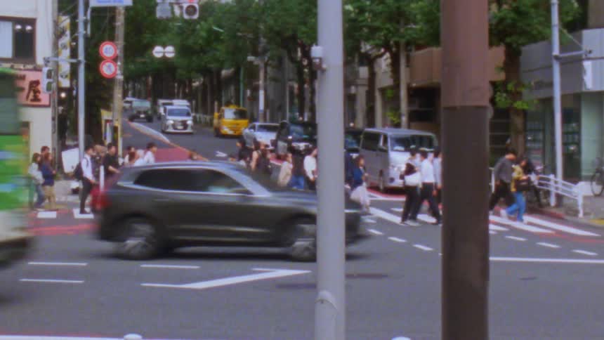 Pedestrians cross a road at a busy intersection in a city