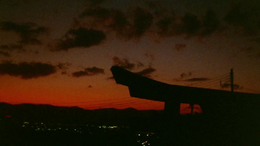 Silhouette of a structure with an orange sky at sunrise with dark clouds