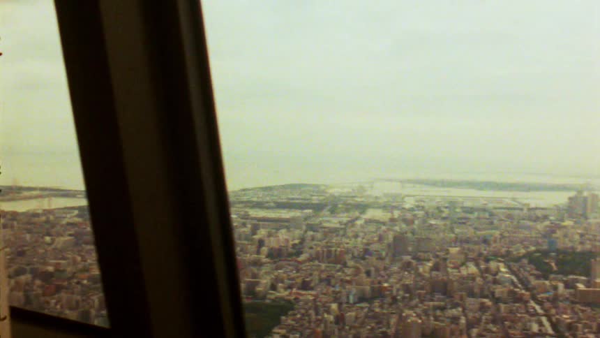 A cityscape and river are visible through the large windows of a highrise building under overcast skies