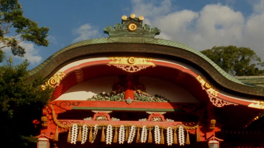 An ornate temple with ribbons blowing in the breeze is nestled in the trees