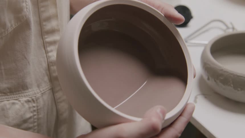 A woman swirls water around in a fresh pottery bowl