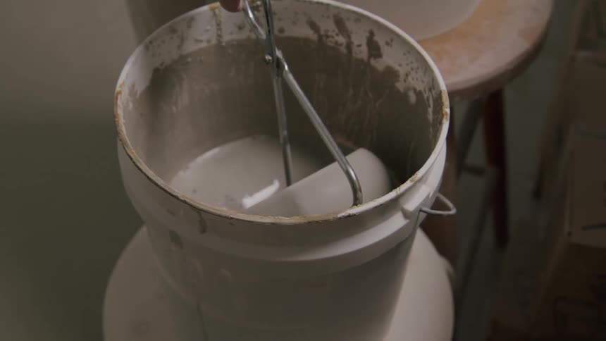 A person using tongs carefully lowers a new pottery bowl into a bucket of water