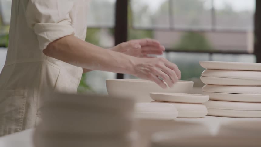 A woman moves new pottery around on a table