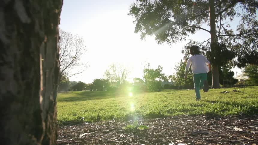 Child running towards the sun on a field