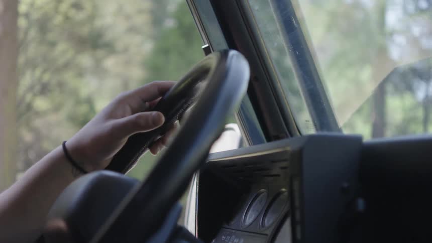 A man's hands on the steering wheel as he drives