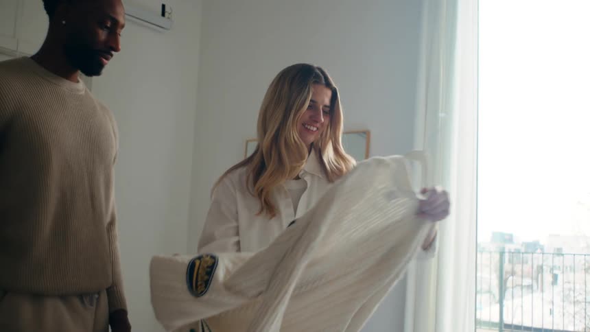 A man and woman examine clothing as they put them down