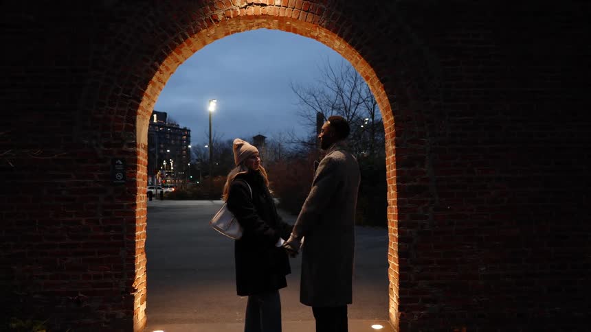 A couple kiss and dance under the archway
