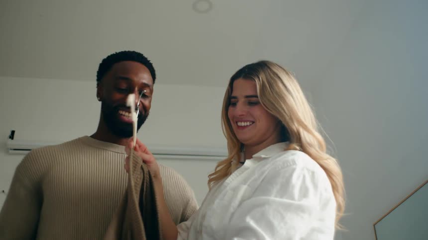 A young couple tries on clothes in a welllit room
