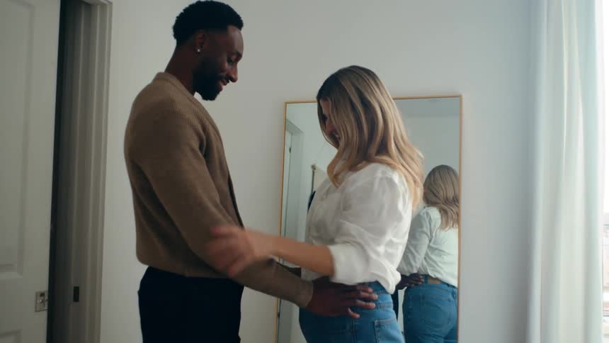 A couple of a man and a woman who are happy and are holding hands and looking at each other in a mirror