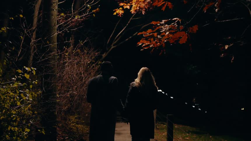 A couple hold hands and walk on the sidewalk