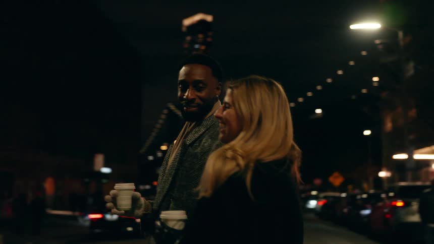 Couple holding hands walking through the city at night