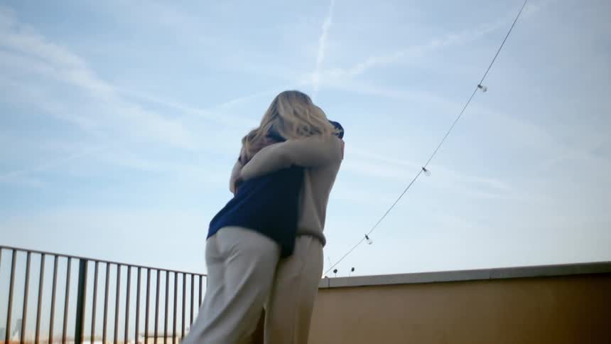 A man picks up a woman and spins her around on a balcony