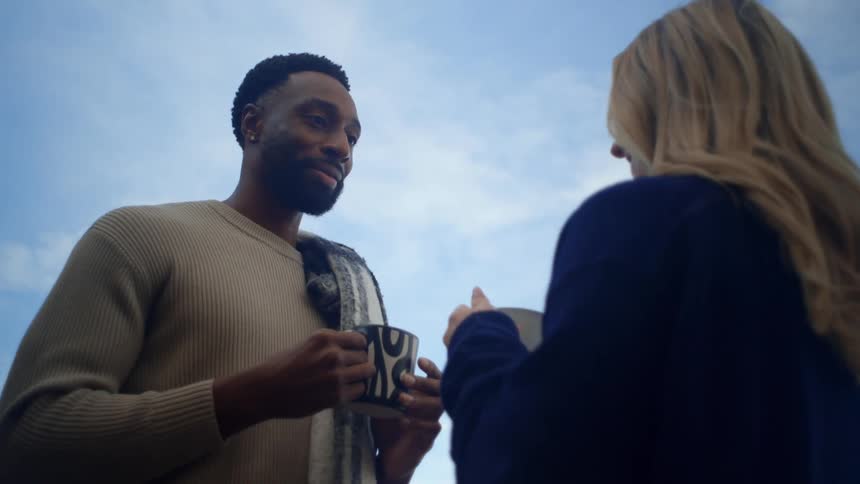 A man and woman toast mugs outside