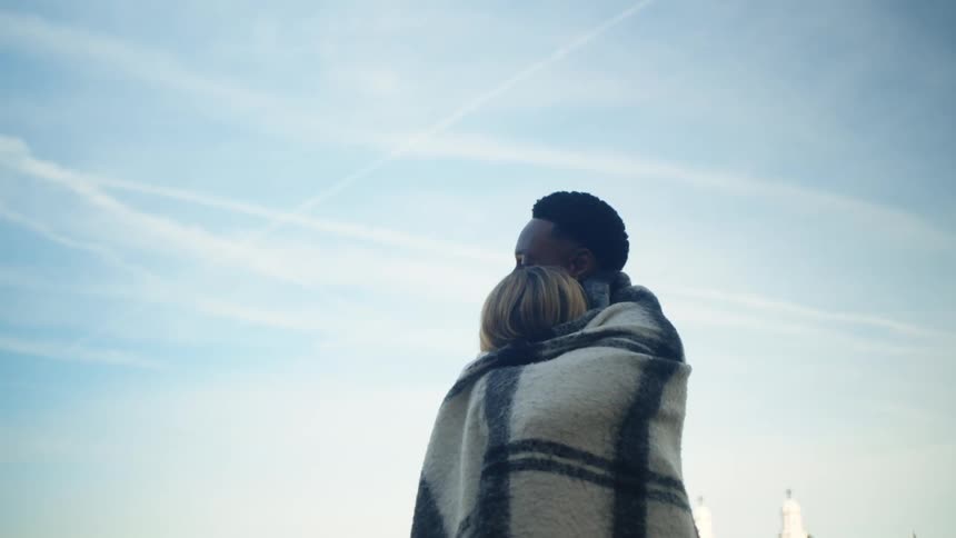 Couple cuddling together on a blanket in the open air