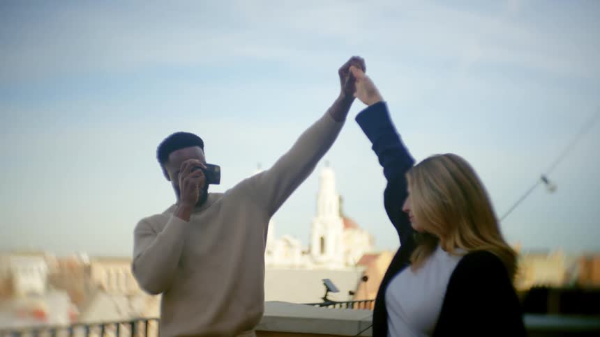A man twirls a woman as he photographs her