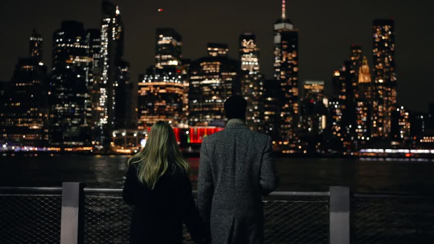 Couple walking together hugging through the city at night and by the sea