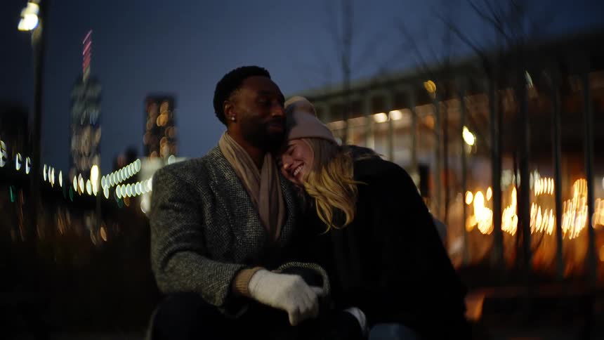 Couple cuddling together sitting outdoors at night