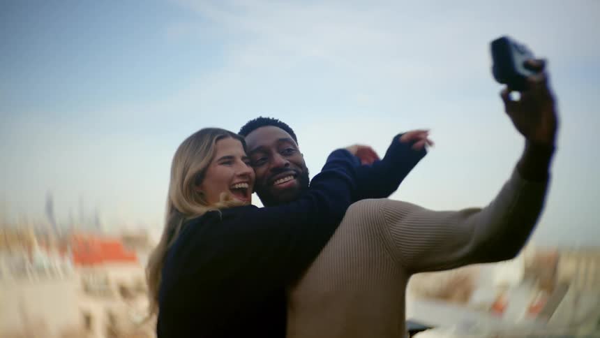 A couple smiles and hugs as they take a selfie photo