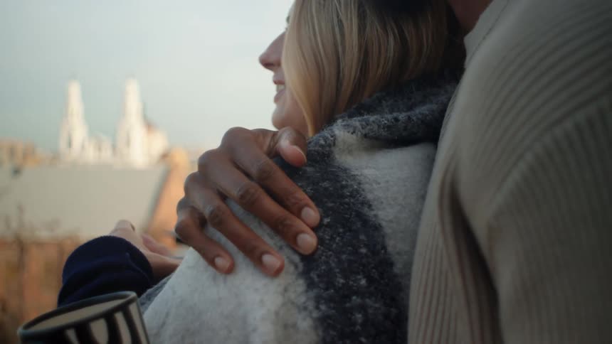A man and woman hug and have drinks outside