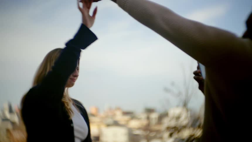 A woman smiles and dances as a man takes her picture