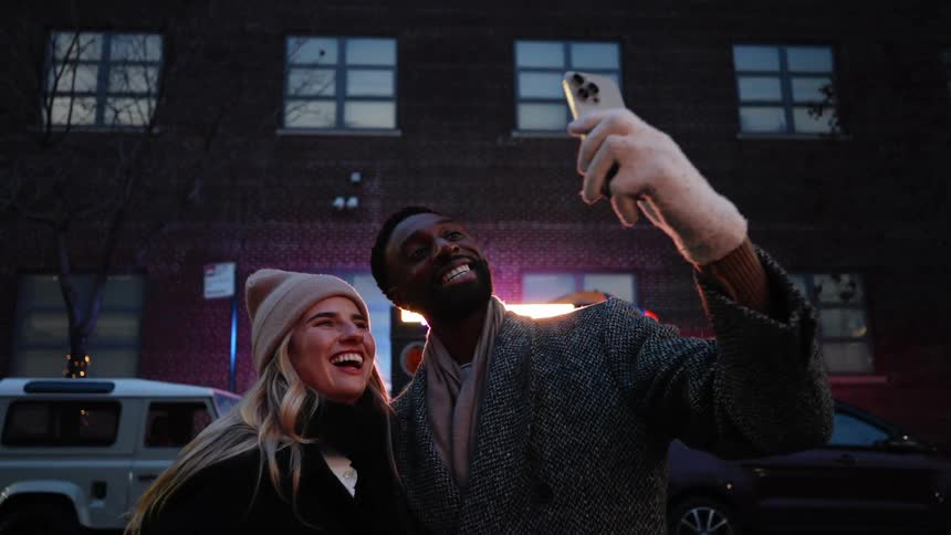 Couple outdoors at night in the city taking a selfie happily