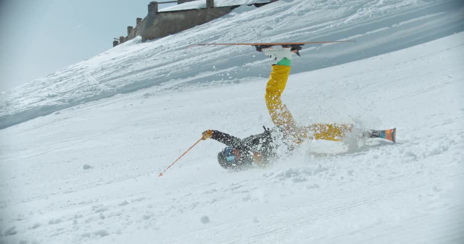 A man jumps on his skis on a mountain then falls