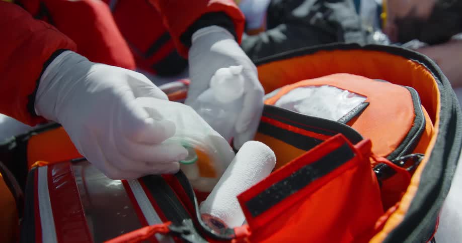 Pair of gloved hands picking up first aid equipment