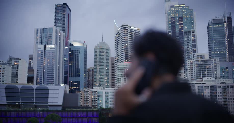 A man is talking on his cell phone in front of the city