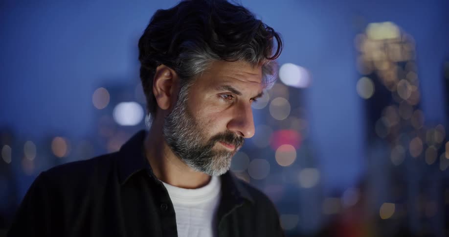 A man looks around at the buildings behind him