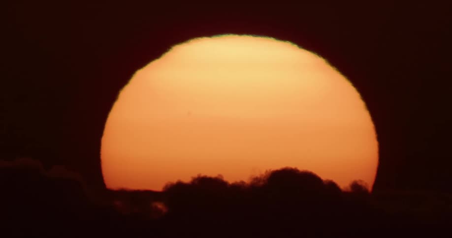 Clouds flow by the rising sun