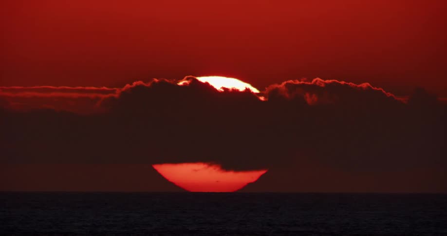 Clouds passing in front of the sun over the ocean during dusk or dawn
